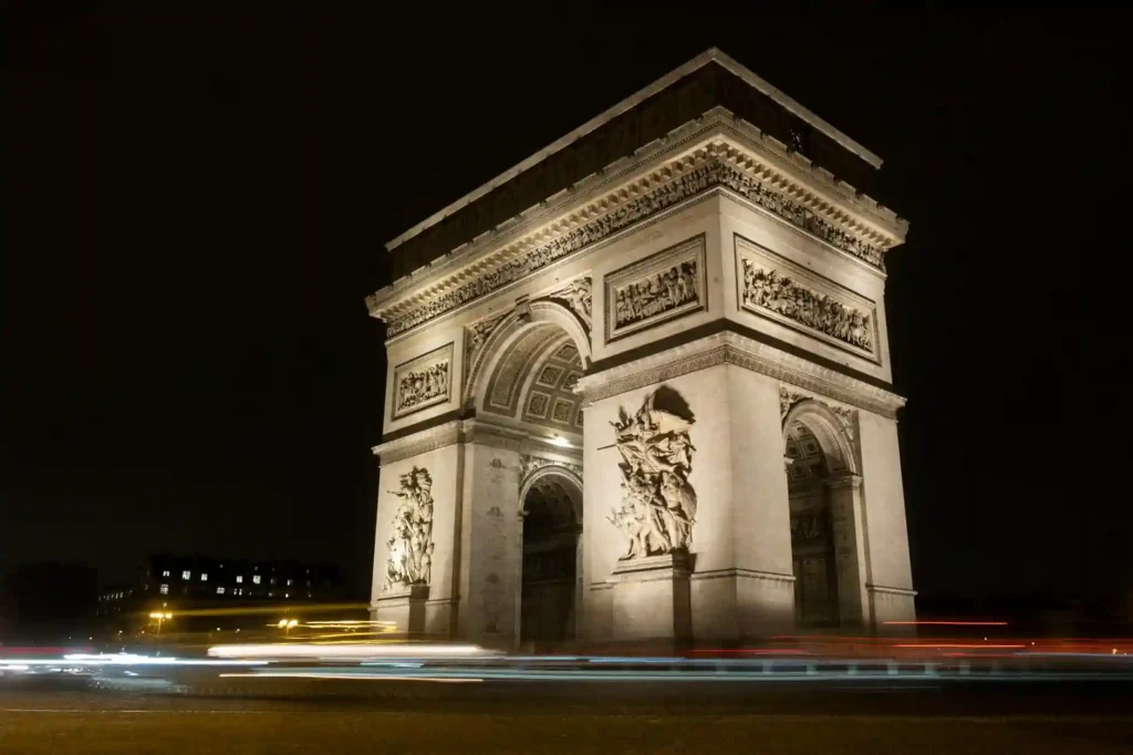 Illuminated Arc de Triomphe at night with light trails in Paris