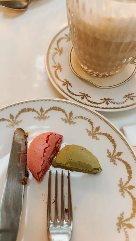 Ladurée Parisian tea set with half-eaten raspberry and pistachio macarons on elegant china