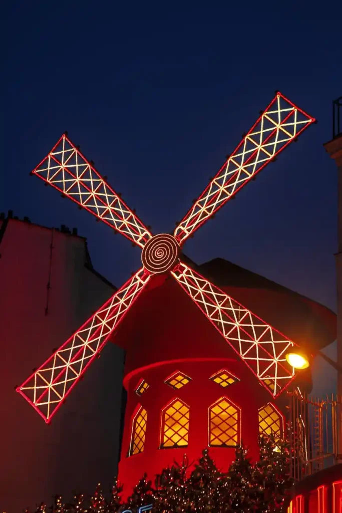 Iconic red windmill of Moulin Rouge illuminated at night in Montmartre, Paris
