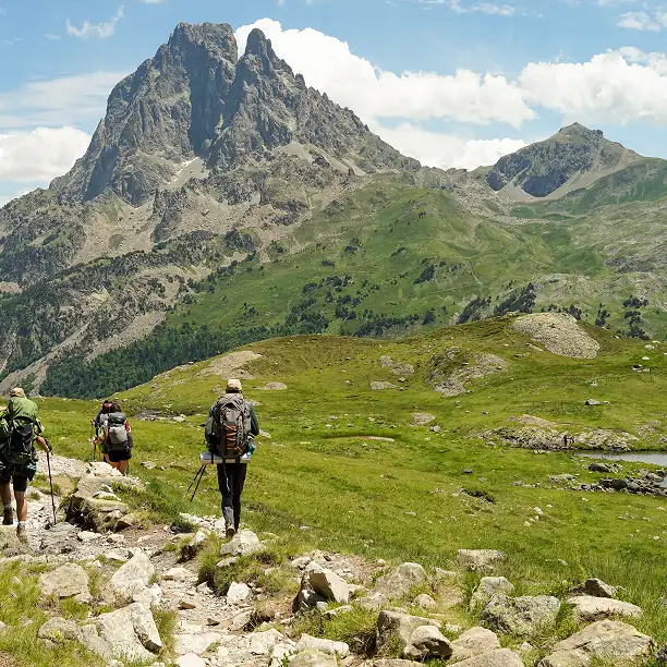 Group hiking in the French Alps beneath a towering mountain peak