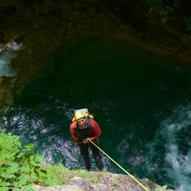 Traveler descending into a canyon with lush vegetation and turquoise water