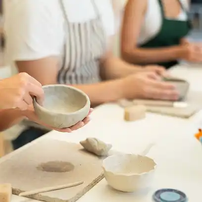 Hands shaping clay in a sunlit French pottery studio