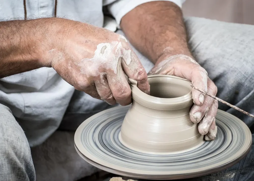 Hands shaping clay on a pottery wheel in a traditional workshop