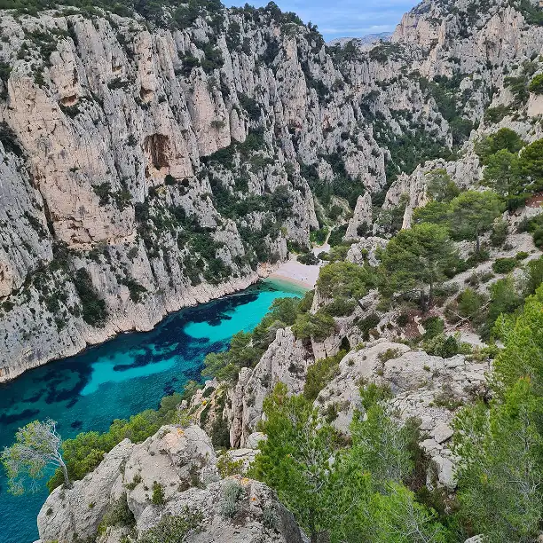 People hiking along rocky cliffs with sweeping views of the Mediterranean