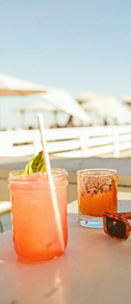 Sunset cocktails and sunglasses on a beach club table in the French Riviera