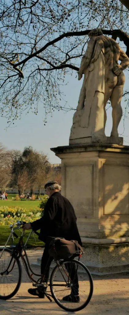 Man with a bicycle in a Parisian park under early spring light