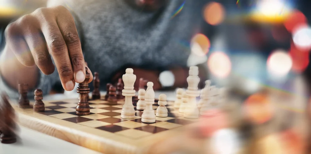 Hands moving chess pieces on a wooden board in a cozy setting