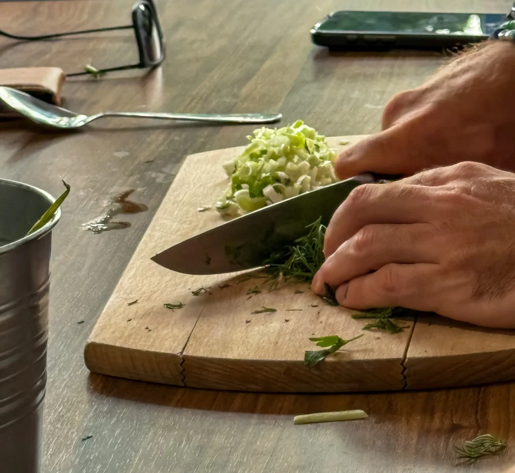 Hands chopping fresh herbs on a wooden board during a French cooking class as part of luxury wine tours in France
