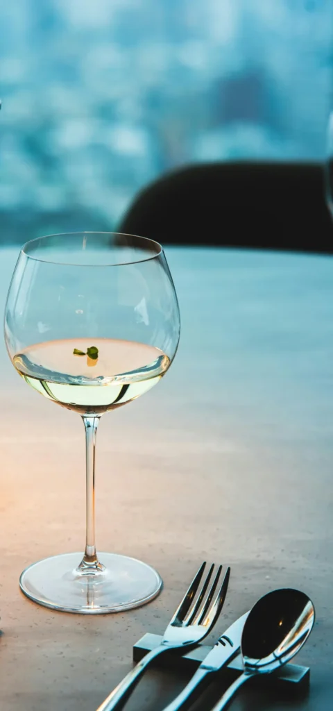Glass of white wine on a seaside restaurant table at dusk