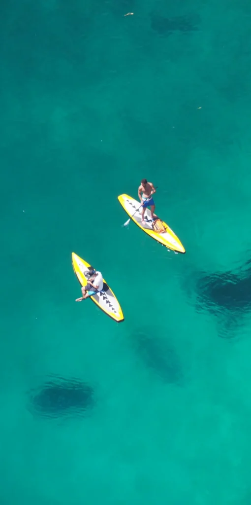 Two people kayaking in vibrant turquoise waters from above