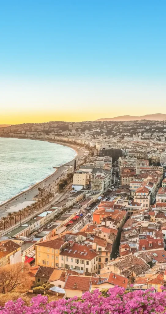 Panoramic view over the rooftops and beach promenade of Nice at sunset