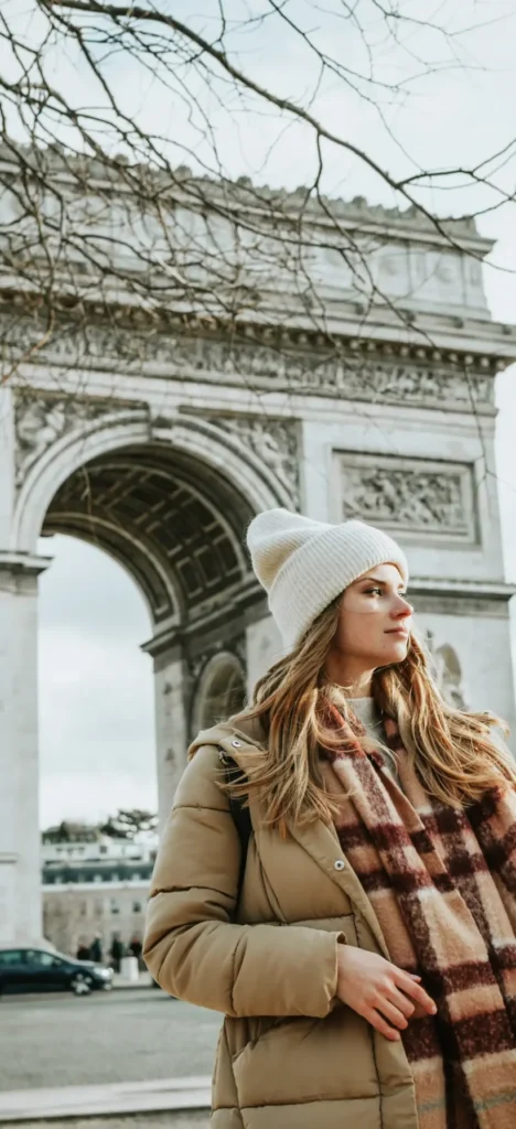 Elegant woman in winter outfit standing near the Arc de Triomphe