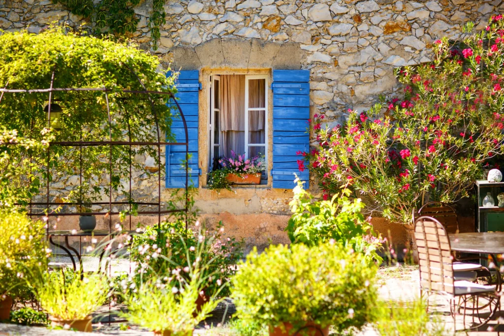 Sunlit stone house with blue shutters in a charming Provençal village