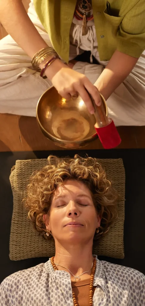 Therapist performing a sound bath with a singing bowl in a wellness setting during exclusive wellness travel in France