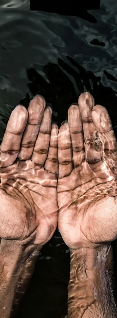 Hands cupping water in a spa setting with a calming dark background