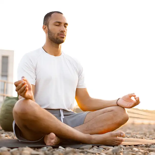 Man in lotus pose meditating during a sunset yoga session