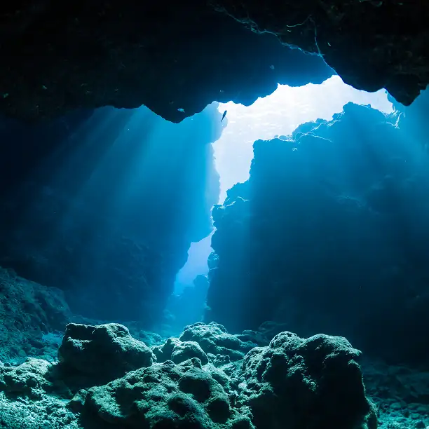 Sunlight streaming into an underwater grotto with crystal-clear water