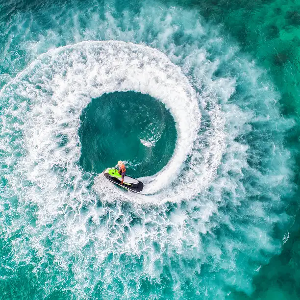 Person on a jetboard creating a perfect circular splash in turquoise sea