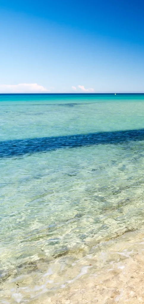 White sandy beach and wooden pier stretching into turquoise waters