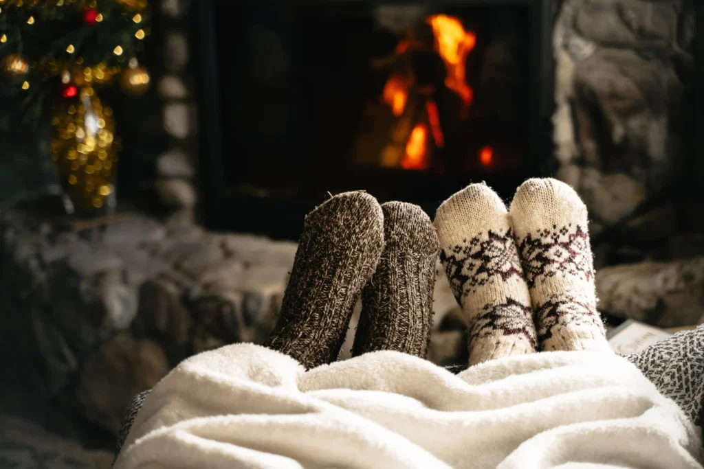 Warm blankets and hot drink near a glowing winter fireplace