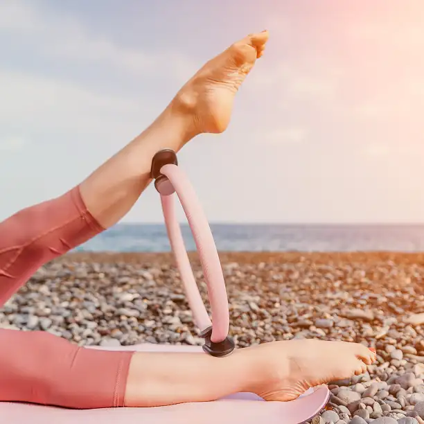 Woman practicing yoga at sunrise on a beach with ocean in the background