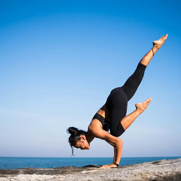Woman practicing yoga on a quiet beach in France at sunrise