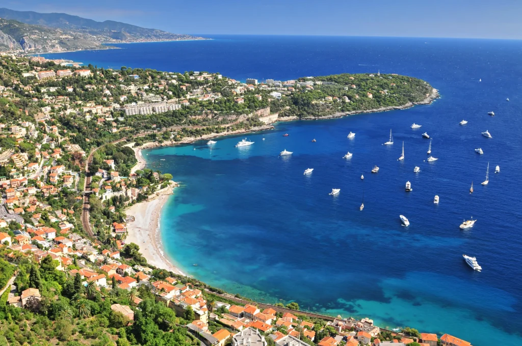 Aerial view of Beaulieu-sur-Mer on the French Riviera with turquoise waters and anchored boats, a luxury travel destination in France.