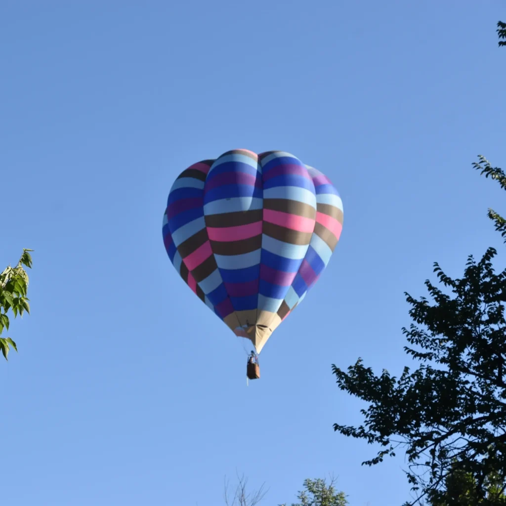 Colorful hot air balloon floating above the trees in Provence