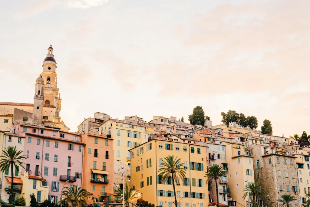 Luxury travel in Monaco and Menton with pastel harborfront houses at sunset