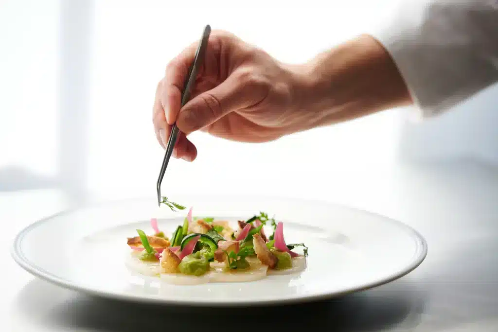 Dining in Paris : Chef using tweezers to plate a refined French dish in a Michelin style restaurant in Paris