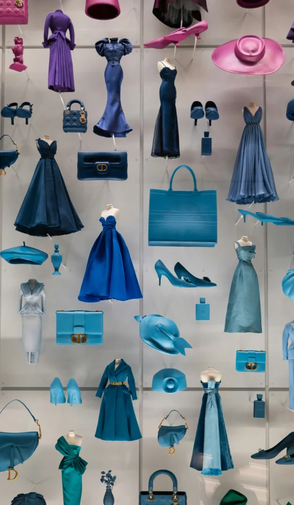Collection of elegant blue evening gowns and luxury fashion accessories displayed on light background