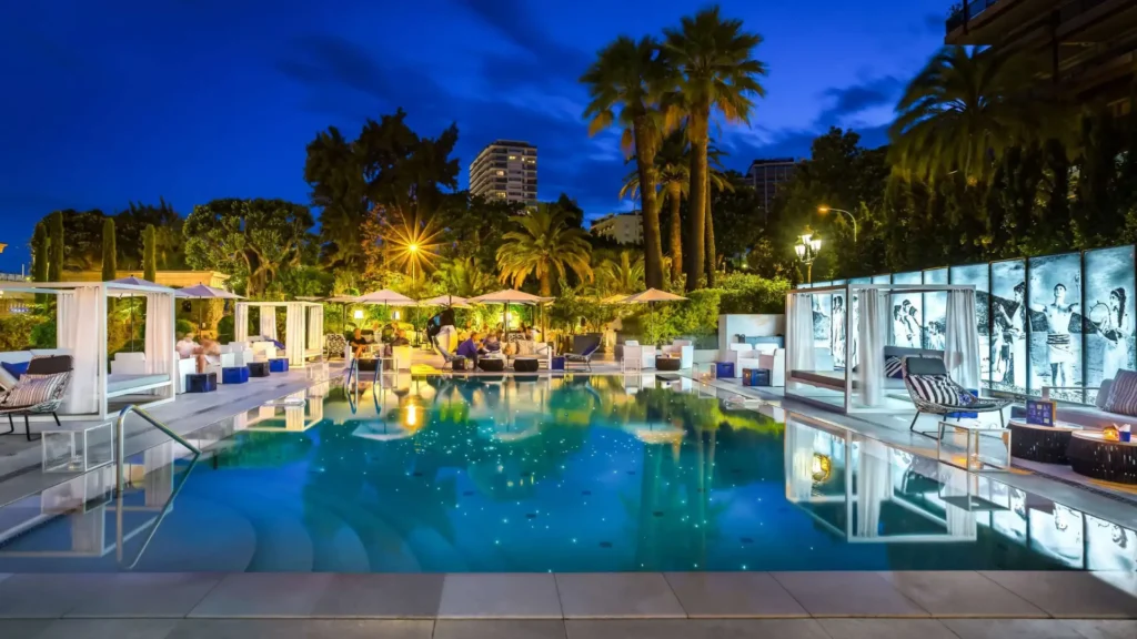 Exclusive evening ambiance at Hotel Metropole Monte-Carlo featuring illuminated infinity pool surrounded by Mediterranean gardens