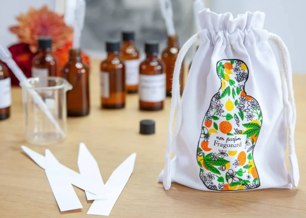 Menton, Elegant white drawstring pouch with luxury French perfume bottles and essential oils arranged on natural surface