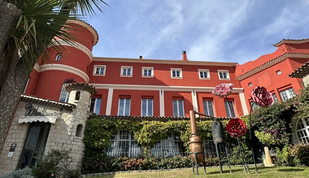 Elegant red villa with manicured gardens and palm trees on the French Riviera