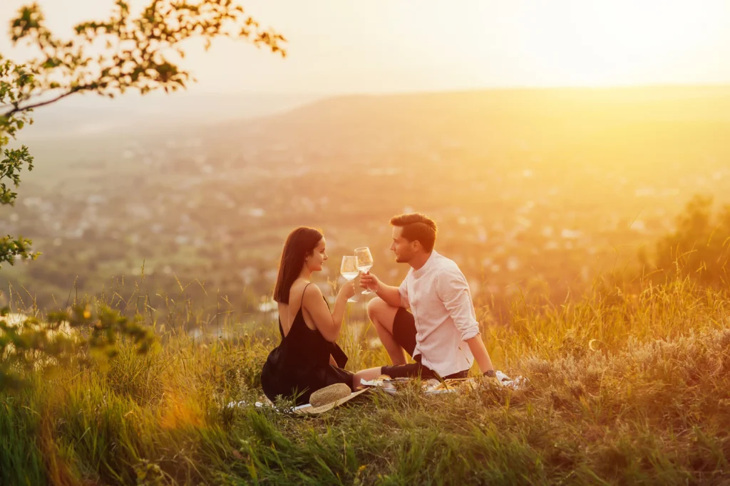 French honeymoon, Romantic couple enjoying sunset picnic with champagne at scenic mountain overlook