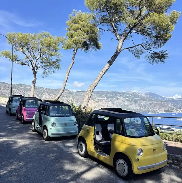 Vintage car on panoramic coastal road overlooking turquoise Mediterranean Sea and pine trees on French Riviera