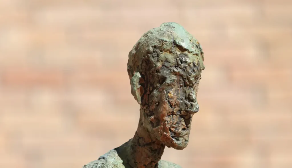 Weathered bronze sculpture bust with natural green oxidized patina and textured surface