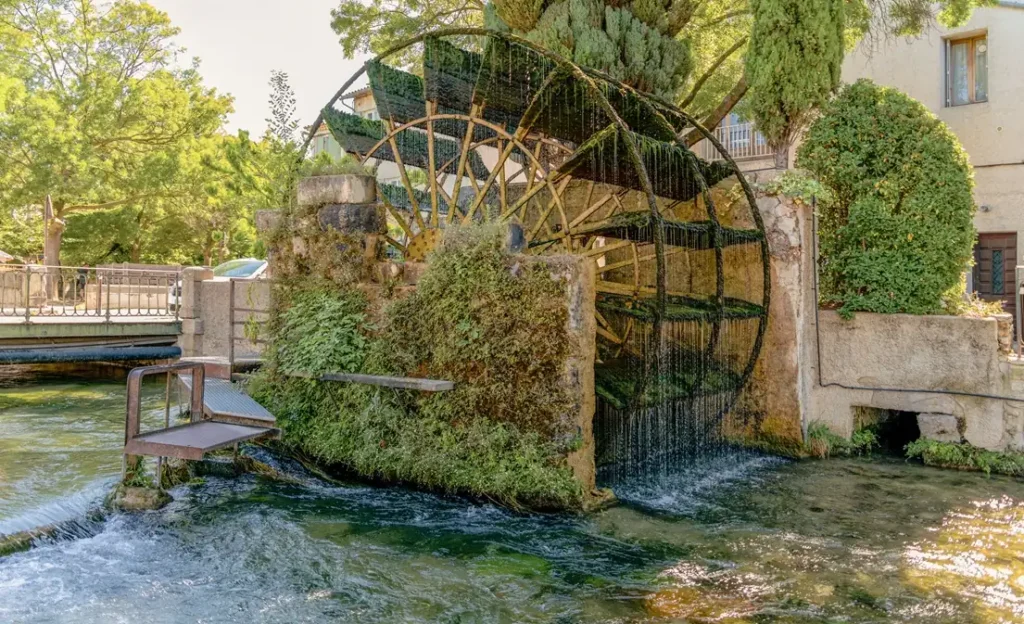 Historic stone bridge over canal lined with plane trees in Provence