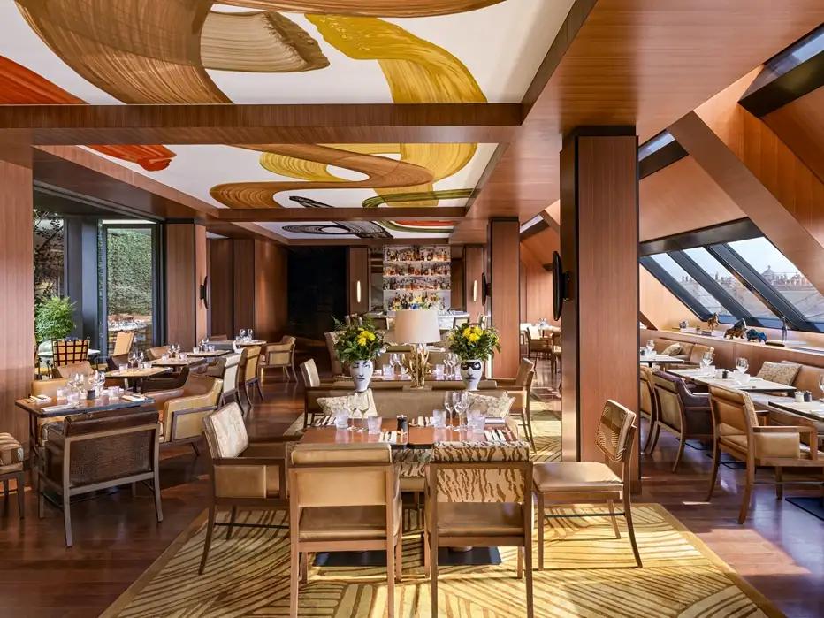Warm wood interior of La Plume restaurant in Paris with large windows, greenery and chic table settings.