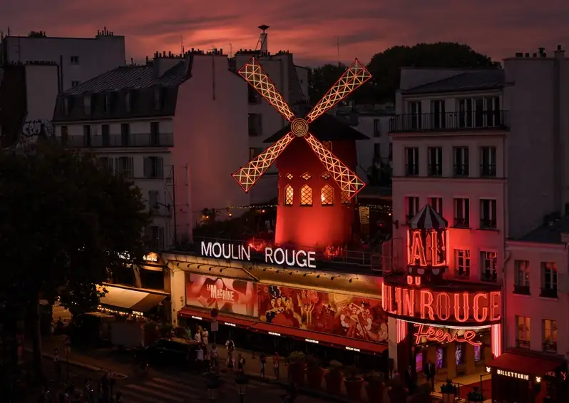 Iconic Moulin Rouge cabaret illuminated at night with red windmill on rooftop in Pigalle Paris