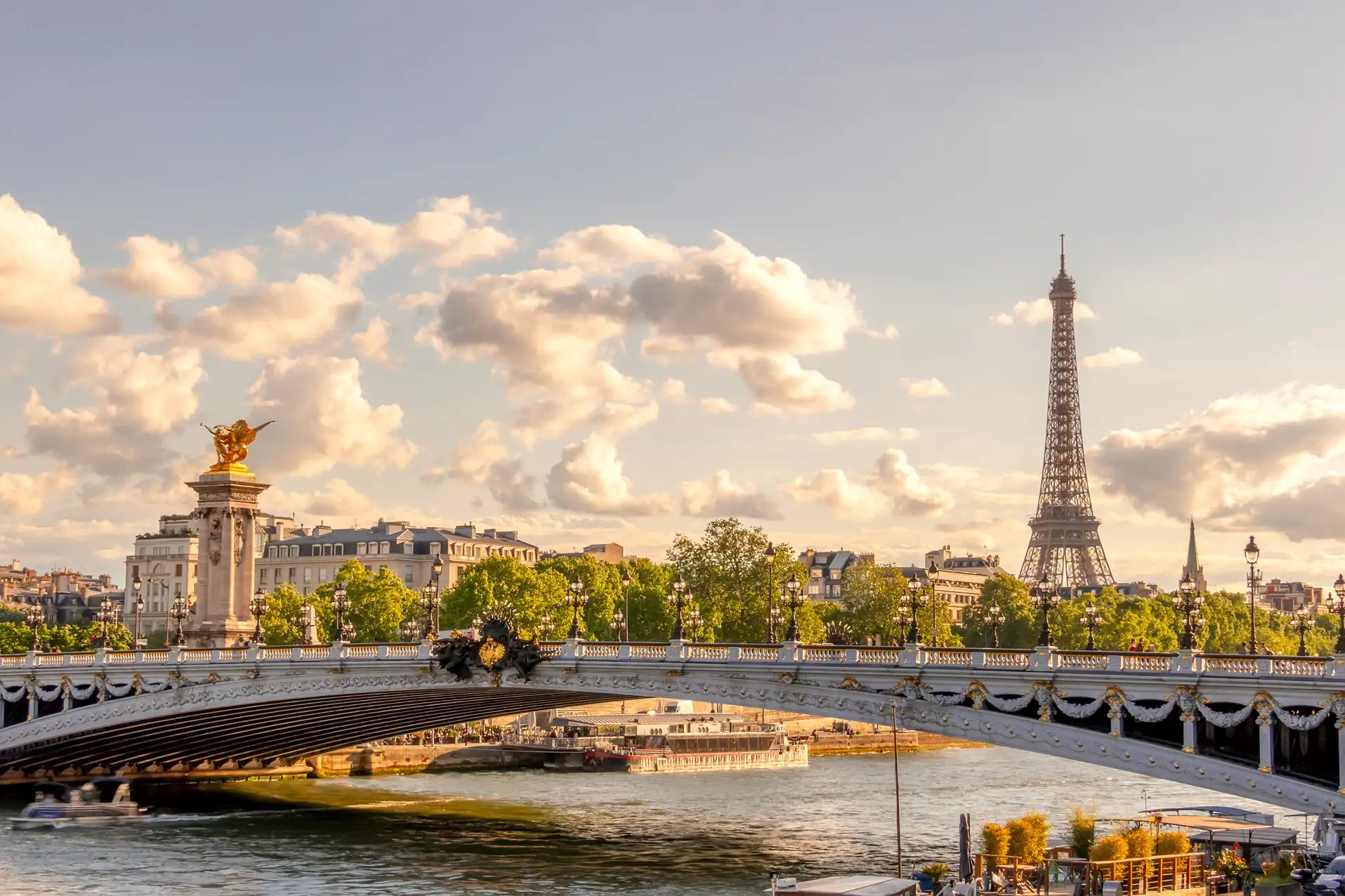 Sunset over the Seine River and Eiffel Tower in Paris with golden sky and city bridges.