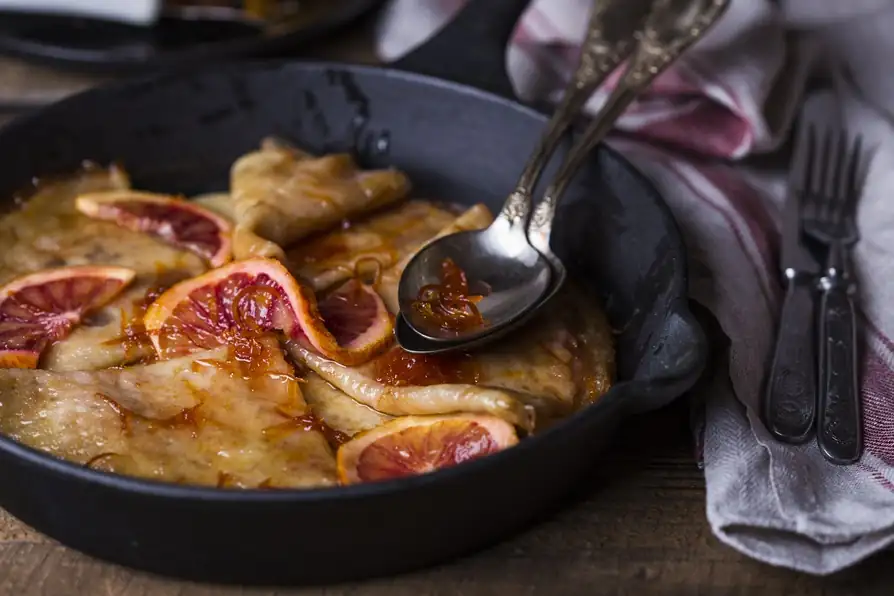 Close-up of warm French dessert with caramelized figs in a skillet on a rustic table.