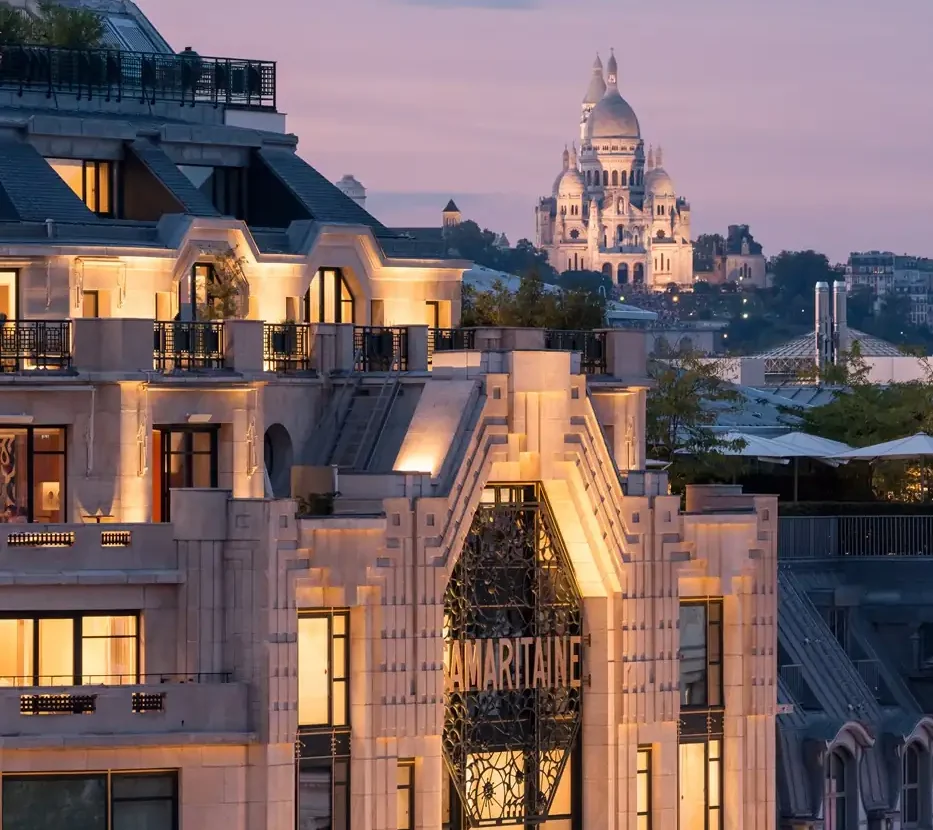 Paris departments stores, Parisian rooftops at sunset with Sacré-Cœur Basilica illuminated on Montmartre hill in the background