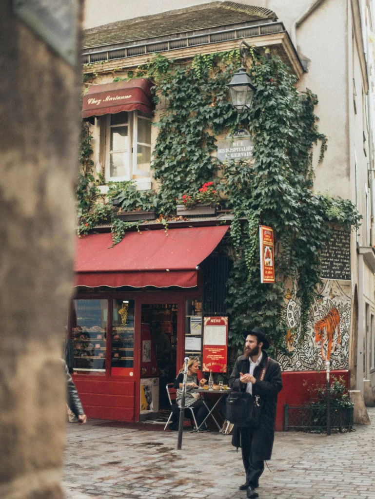 Charming street café in Le Marais, Paris, with ivy-covered buildings and intimate atmosphere