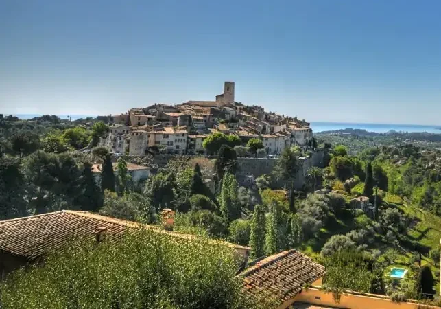 Panoramic view of Saint-Paul-de-Vence, a hilltop village in Provence, overlooking the French Riviera countryside under a clear blue sky.