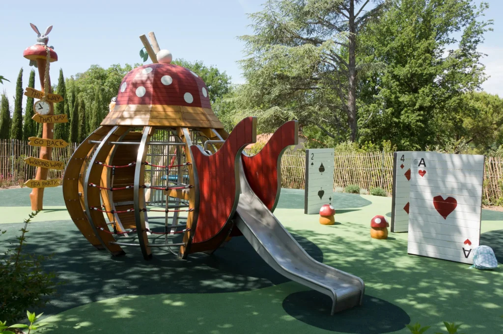 Whimsical children's playground with Alice in Wonderland themed structures and giant playing cards