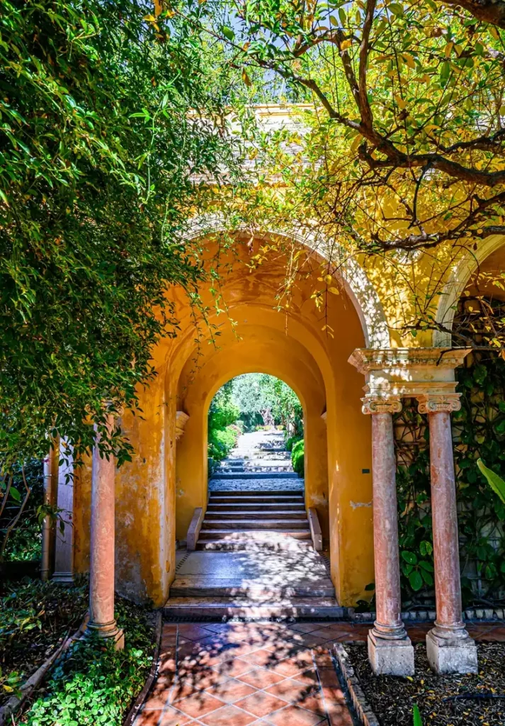 Enchanting garden archway covered in golden autumn foliage creating natural tunnel effect