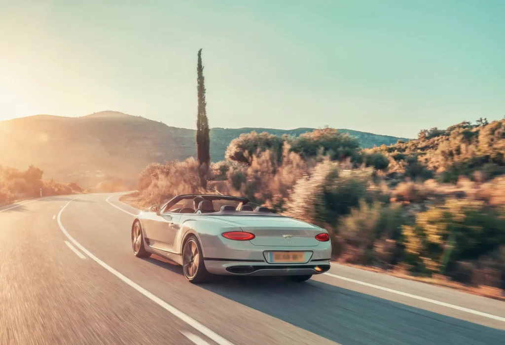 Driving a classic vintage convertible car along a scenic coastal road in the South of France at sunset