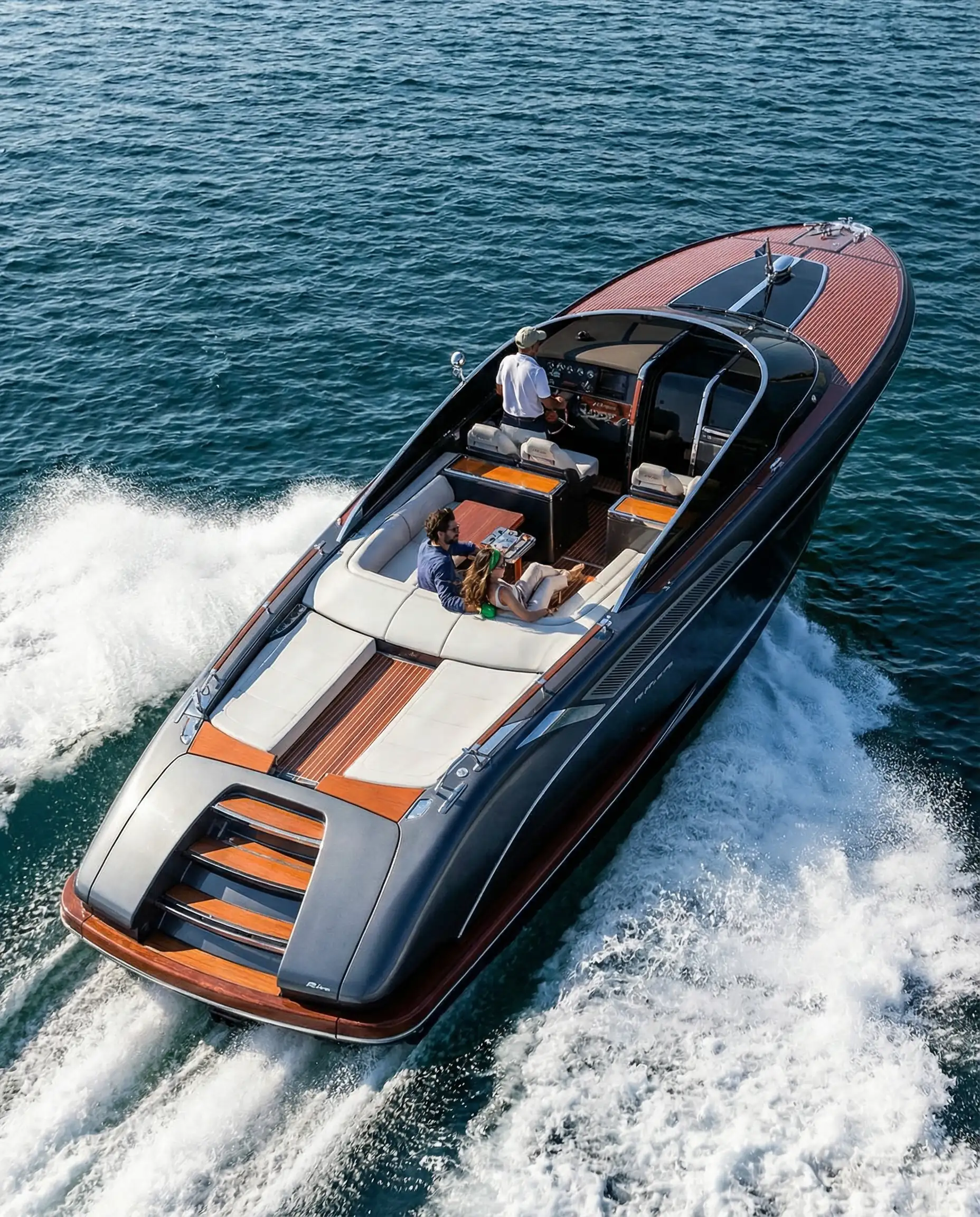 Aerial view of a sleek navy blue and teak wood luxury speedboat cruising through deep blue ocean waters.