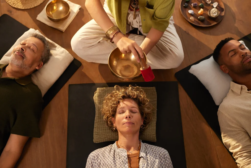 wellness travel France, Sound healing session with people lying down and practitioner using a singing bowl